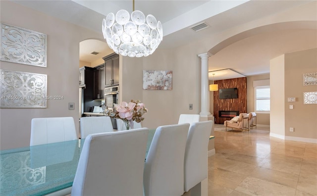 dining room with a large fireplace, a notable chandelier, and decorative columns