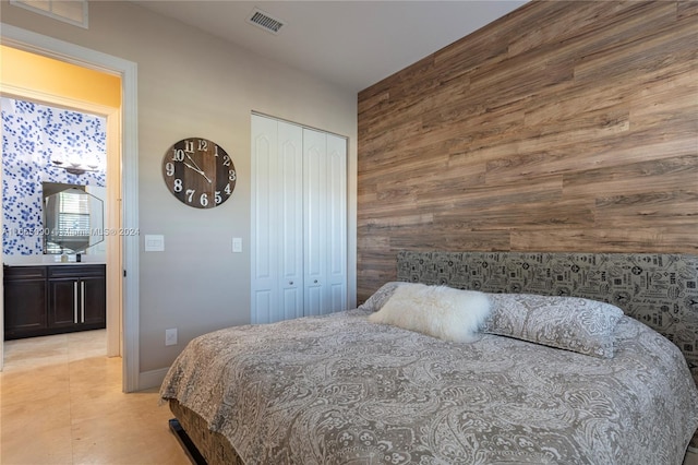 tiled bedroom with a closet, wooden walls, and sink