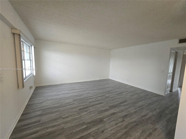 empty room with dark hardwood / wood-style flooring and a textured ceiling