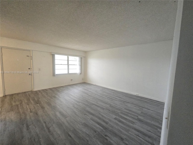 spare room featuring a textured ceiling and dark hardwood / wood-style flooring