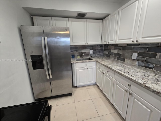 kitchen featuring black range, light stone countertops, stainless steel refrigerator with ice dispenser, sink, and white cabinets