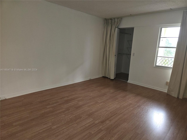 unfurnished room with dark hardwood / wood-style flooring and a textured ceiling