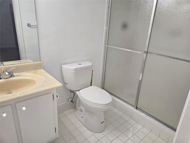 bathroom featuring a shower with door, vanity, toilet, and tile patterned floors