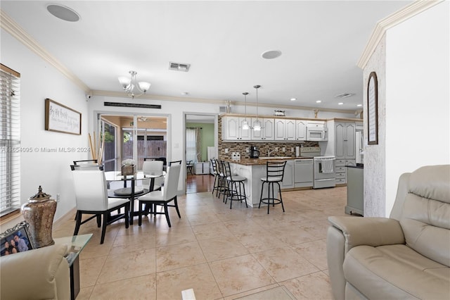 tiled living room with crown molding and a notable chandelier