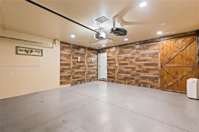 garage with a garage door opener and wooden walls