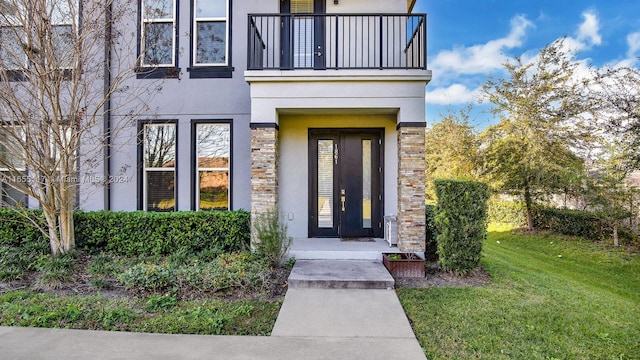 entrance to property featuring a balcony and a yard