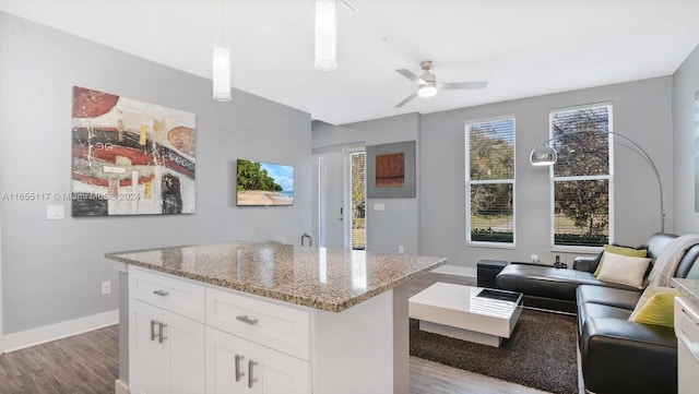 kitchen with decorative light fixtures, light hardwood / wood-style floors, a center island, ceiling fan, and white cabinets