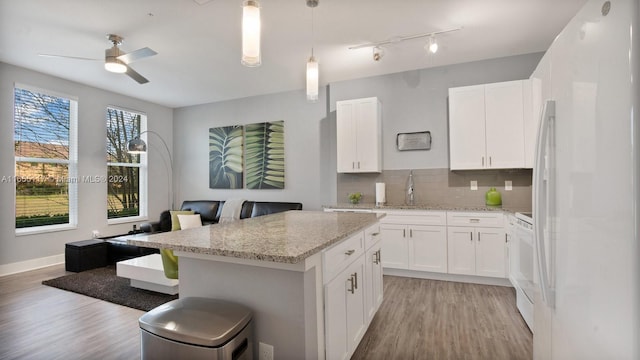 kitchen with white appliances, hanging light fixtures, white cabinetry, ceiling fan, and light wood-type flooring