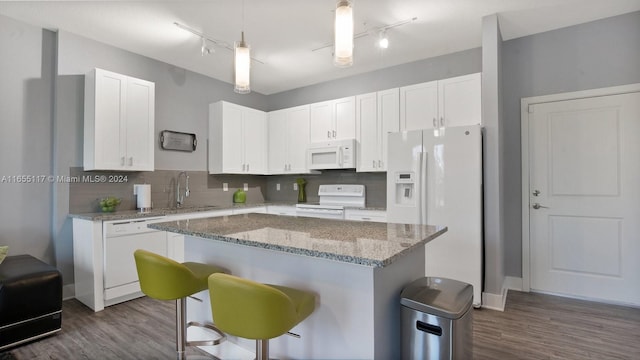 kitchen with a kitchen island, dark hardwood / wood-style floors, white appliances, a kitchen bar, and white cabinets