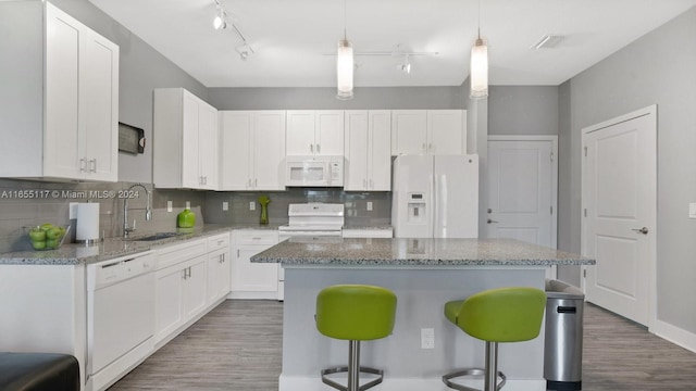 kitchen featuring white cabinetry, white appliances, a kitchen bar, a kitchen island, and sink