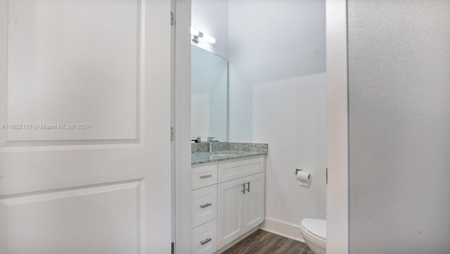 bathroom with vanity, toilet, and hardwood / wood-style floors