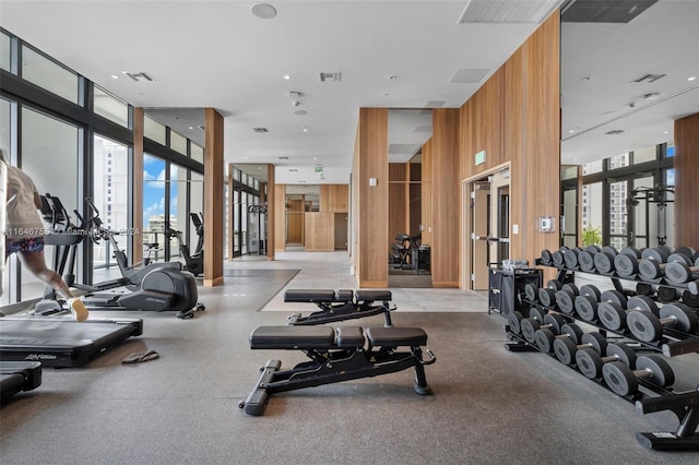 exercise room featuring wood walls and a wall of windows