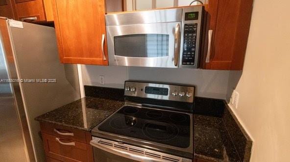 kitchen featuring stainless steel appliances and dark stone counters