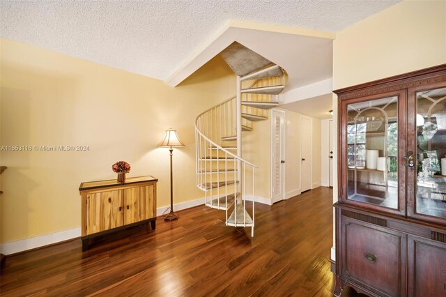 entrance foyer with a textured ceiling, dark hardwood / wood-style floors, and lofted ceiling