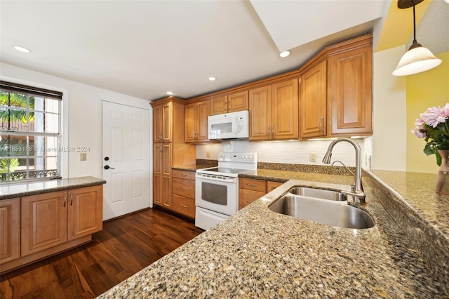 kitchen featuring dark hardwood / wood-style floors, white appliances, tasteful backsplash, sink, and dark stone countertops