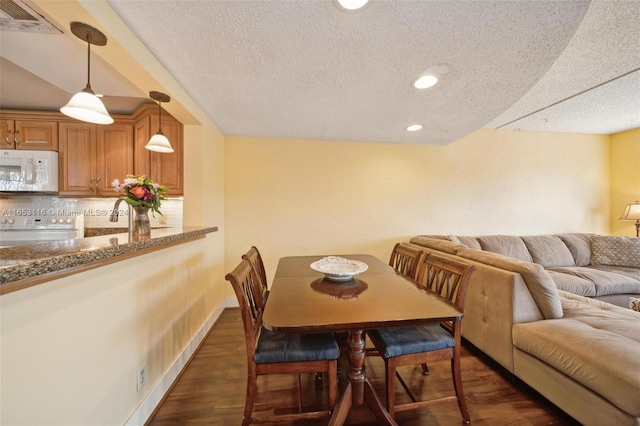 dining room featuring dark wood-type flooring and a textured ceiling