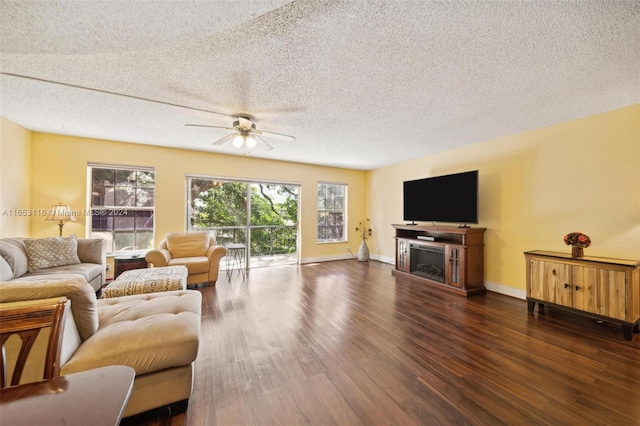 living room with a textured ceiling, dark wood-type flooring, ceiling fan, and a fireplace