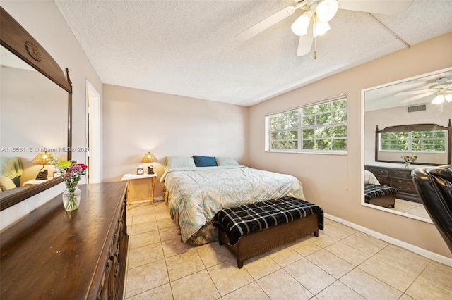 bedroom with a textured ceiling, light tile patterned floors, and ceiling fan