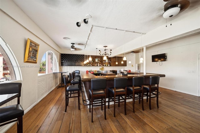 dining space with bar area, ceiling fan, and dark hardwood / wood-style floors