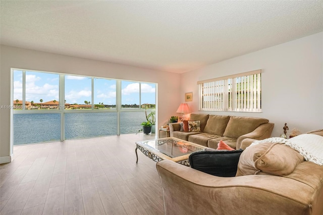 living area with a water view, a textured ceiling, and wood finished floors