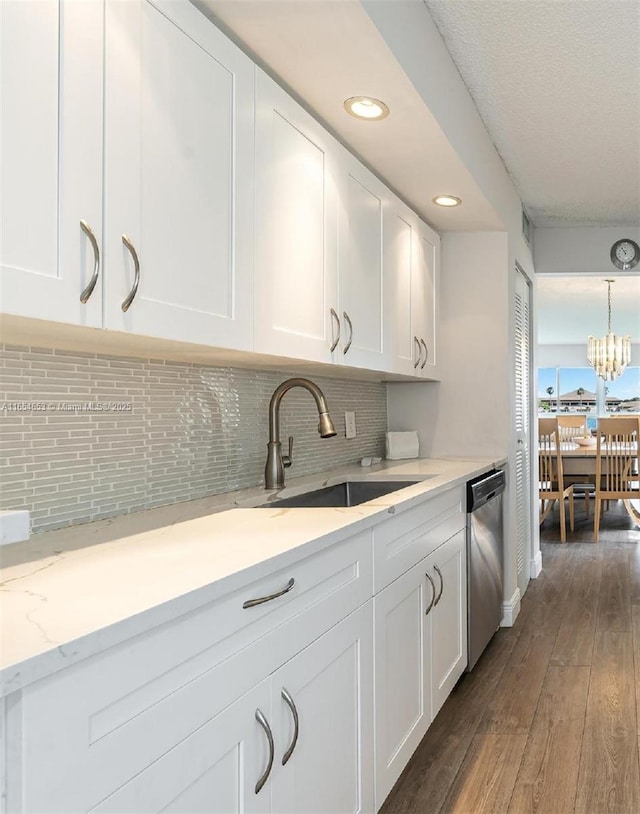 kitchen featuring wood finished floors, a sink, white cabinets, stainless steel dishwasher, and backsplash