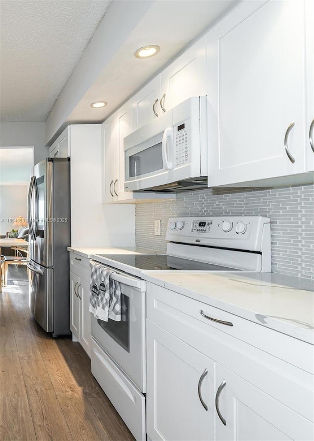 kitchen featuring white appliances, decorative backsplash, dark wood-type flooring, light countertops, and white cabinetry