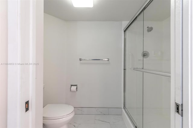 bathroom featuring toilet, marble finish floor, baseboards, and a stall shower