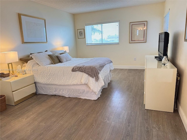 bedroom featuring a textured ceiling, dark wood finished floors, and baseboards