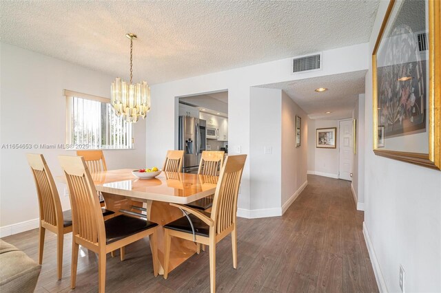 dining room featuring dark hardwood / wood-style flooring, an inviting chandelier, and a textured ceiling