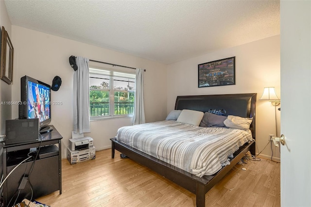 bedroom with a textured ceiling and light hardwood / wood-style floors