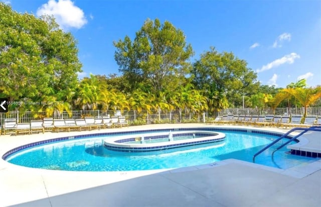 community pool featuring a community hot tub, a patio area, and fence