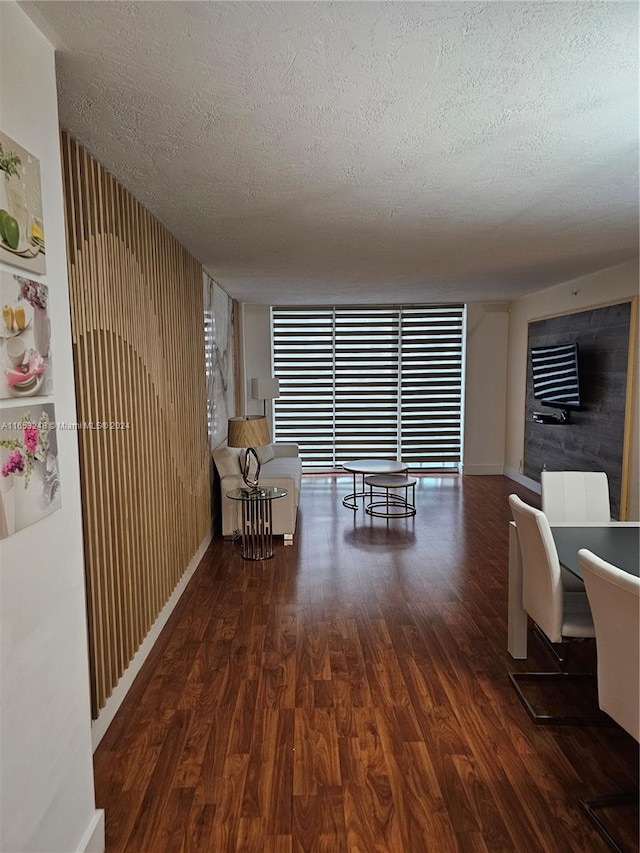 interior space featuring a textured ceiling, a wall of windows, wood walls, and dark hardwood / wood-style floors