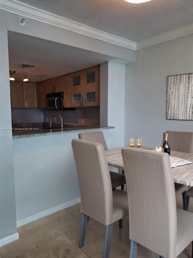 dining space with light tile patterned flooring and crown molding