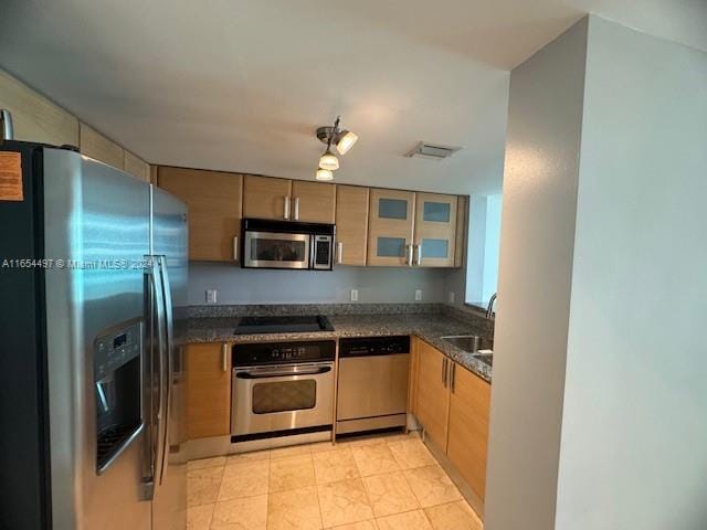 kitchen with dark stone countertops, sink, and stainless steel appliances