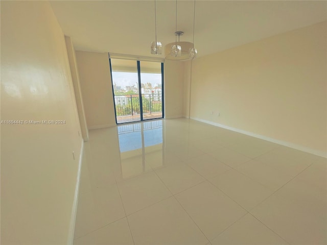 tiled spare room with a notable chandelier and floor to ceiling windows