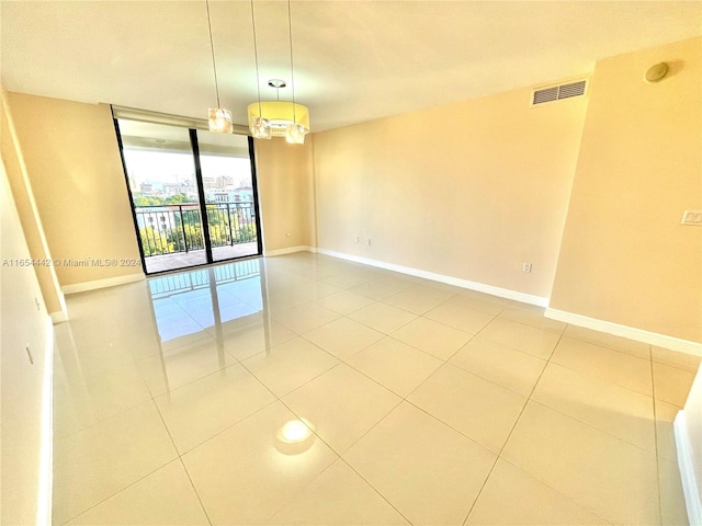 spare room featuring expansive windows, a notable chandelier, and light tile patterned floors