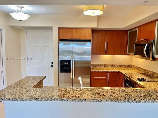 kitchen featuring sink, light stone countertops, kitchen peninsula, and black appliances