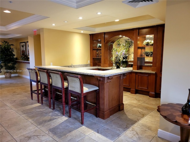 bar featuring light stone countertops, a raised ceiling, and crown molding