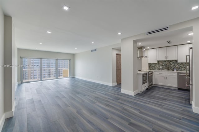 unfurnished living room with dark wood-style flooring, visible vents, and baseboards