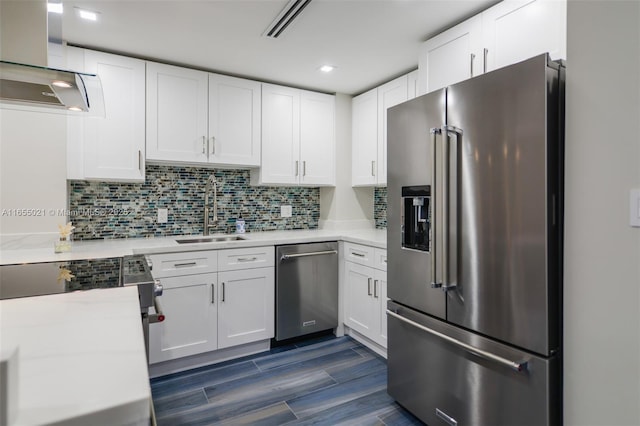 kitchen with stainless steel appliances, a sink, white cabinets, light countertops, and range hood