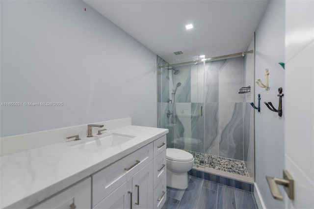 bathroom with toilet, visible vents, vanity, a marble finish shower, and wood tiled floor