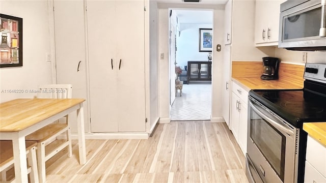 kitchen with stainless steel appliances, white cabinetry, and light hardwood / wood-style floors