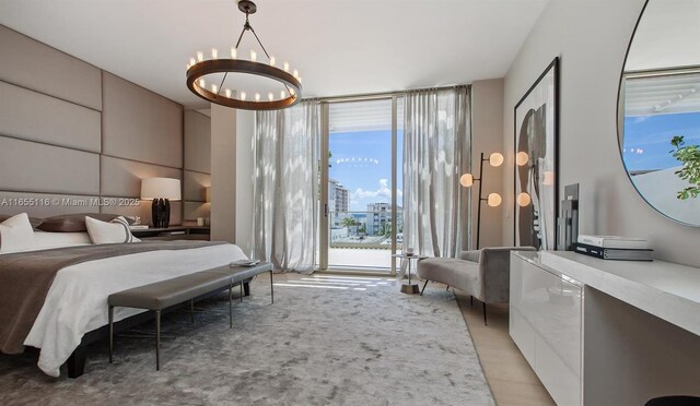 bedroom featuring multiple windows, a wall of windows, and an inviting chandelier