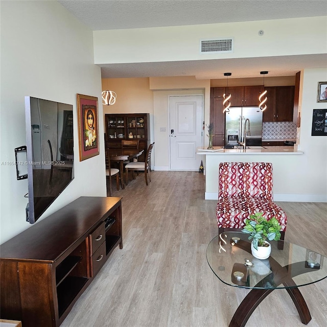 living room with a textured ceiling and light wood-type flooring