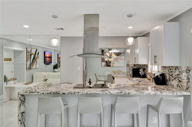 kitchen featuring island exhaust hood, kitchen peninsula, white cabinetry, and decorative light fixtures