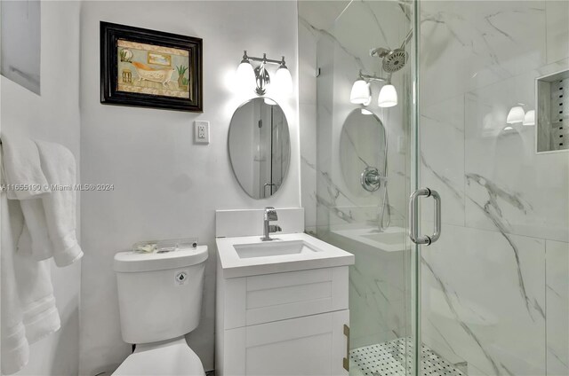 bathroom with vanity, toilet, and a shower with shower door