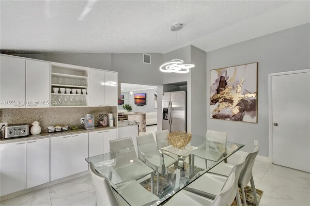 dining space with a textured ceiling and high vaulted ceiling