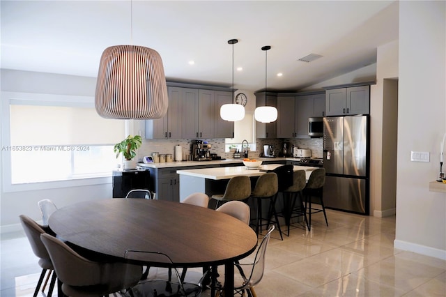 kitchen with gray cabinetry, backsplash, stainless steel appliances, a center island, and decorative light fixtures