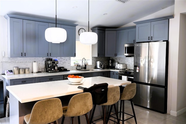 kitchen featuring appliances with stainless steel finishes, backsplash, pendant lighting, a center island, and sink