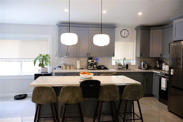 kitchen featuring hanging light fixtures, gray cabinetry, black electric range, a center island, and refrigerator